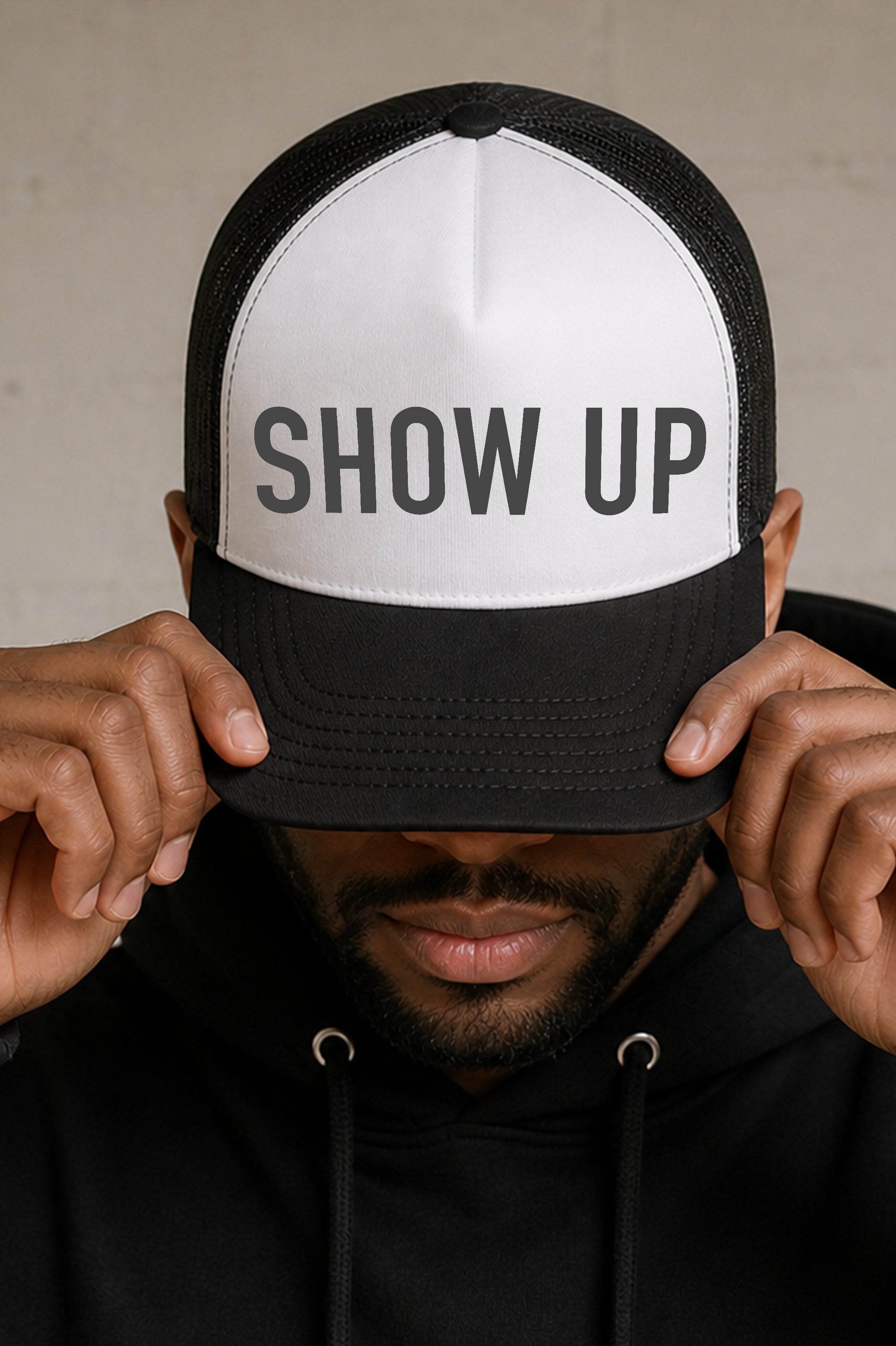 Model wearing a black and white trucker hat featuring a bold gray Show Up graphic from Be Someone's Person, created by content creators Kayla and Samantha.