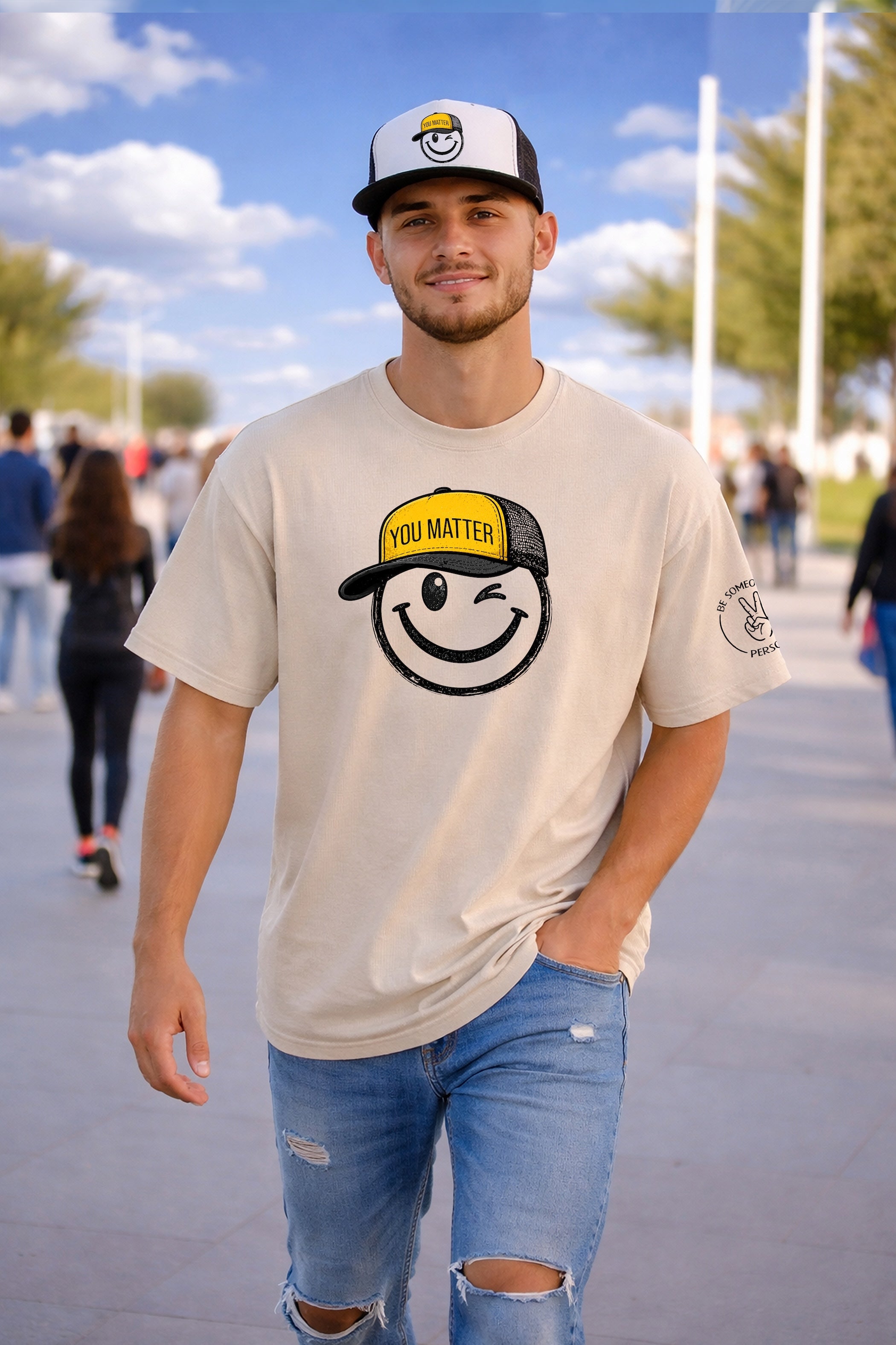 Model wearing a sand unisex t-shirt and matching trucker hat featuring the winking You Matter Smiley face design from Be Someone's Person, created by Kayla and Samantha.